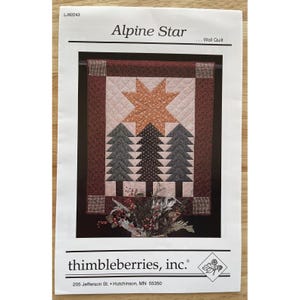 May include: A printed pattern for an "Alpine Star" wall quilt. The quilt design features a large star, three stylized trees, and a patterned border in shades of brown, green, and beige. The pattern is from "thimbleberries, inc."