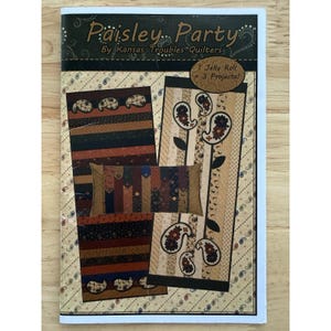 Könnte beinhalten: Ein Patchwork-Musterbuch mit dem Titel "Paisley Party" von Kansas Troubles Quilters. Das Cover zeigt drei Quiltprojekte mit Paisley-Designs in Braun-, Beige- und Rosttönen. Das Buch enthält Anleitungen für ein Jelly Roll-Projekt.