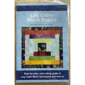 May include: A book titled "Log Cabin Block Basics" with a light blue cover. The cover features a colorful log cabin block design with various colors. The book is a step-by-step guide to log cabin block techniques.