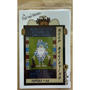 Könnte beinhalten: Ein weihnachtliches Muster mit einer Santa Claus-Figur in einem gemusterten Outfit, die Socken hält. Der Text lautet: "Wenn du aufhörst, an den Weihnachtsmann zu glauben, bekommst du Unterwäsche zu Weihnachten." Das Muster ist mit "Pattern #134" gekennzeichnet.