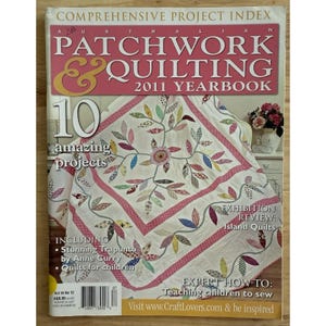 Könnte beinhalten: Das Cover des Magazins "Australian Patchwork & Quilting 2011 Yearbook". Das Cover zeigt einen detaillierten Quilt mit einem Blumen- und Blattdesign in verschiedenen Farben. Das Magazin enthält Artikel über Quiltprojekte, einschließlich Trapunto.