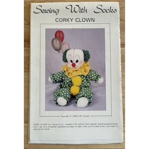 May include: A sewing pattern titled "Corky Clown" featuring a handmade clown doll with a green polka-dot outfit, yellow collar, and three balloons. The text "Sewing With Socks" is at the top.
