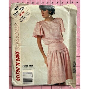 Könnte beinhalten: Ein Vintage-Schnittmuster von McCall's mit einem rosa Kleid mit passendem Oberteil und Rock. Das Muster enthält den Text "STITCH 'N SAVE" und "PETITE-ABLE". Größe B ist für die Größen 12-14-16 angegeben.