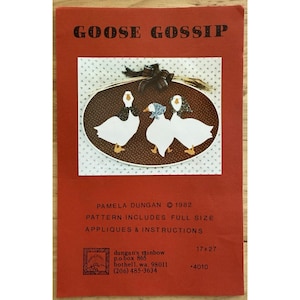 Könnte beinhalten: Ein Vintage-Bastelmuster mit dem Titel "GOOSE GOSSIP" auf rotem Hintergrund. Das Muster zeigt drei weiße Gänse mit schwarzen und blauen Akzenten in einem ovalen Rahmen. Der Text enthält den Namen des Designers, das Jahr und Anweisungen. Das Muster misst 43 x 69 cm.