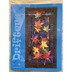 May include: A blue brochure titled "Drifters" featuring a quilt design with colorful autumn leaves. The quilt measures 27 x 52 inches. The brochure includes the text "Inspiring designs, grown from a love of quilting."