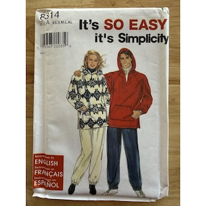 Op de afbeelding: Een naaipatroonpakket met de tekst "It's SO EASY it's Simplicity." De verpakking toont illustraties van twee mensen die een capuchonjas en een broek dragen. De jas links is wit met een blauw en zwart patroon, de andere is rood.