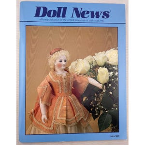 May include: A vintage magazine cover titled "Doll News" with a light blue border. The cover features a doll in an orange dress with a bouquet of white roses. The text "Doll News" is in large, dark blue letters.