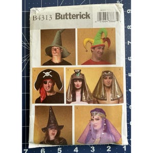 May include: Butterick B4313 sewing pattern envelope featuring illustrations of six different costume headpieces: a green pointed hat, a multi-colored jester hat with bells, a black pirate hat with skull emblem, two gold pharaonic headpieces, and a purple veil.