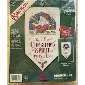 Può includere: Un kit banner a punto croce con la scritta "Keep The Christmas Spirit All Year Long". Il banner presenta un Babbo Natale ricamato a punto croce che suona una tromba. Il banner misura circa 20 cm x 36 cm e include un gancio di filo.