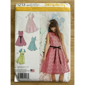 May include: Simplicity sewing pattern 1213 AA for girls' plus sizes 8-16. The pattern features illustrations of various dress designs, including a pink lace dress with a dark brown ribbon belt. The pattern includes the text "Designed and printed in the USA."