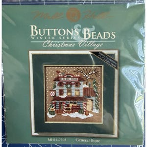 Könnte beinhalten: Ein Mill Hill Buttons & Beads Winter Series Christmas Village Kreuzstich-Set mit einem General Store Motiv. Die Verpackung zeigt das fertige Projekt mit den Maßen von ca. 14 cm x 14 cm und enthält die Modellnummer MH14-7303.