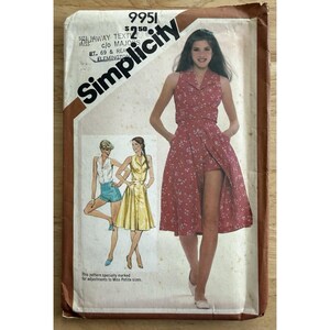 May include: A Simplicity sewing pattern envelope, number 9951, featuring illustrations of a sleeveless dress with a collared bodice and a flared skirt. The main image shows a red dress with a white floral print, while smaller sketches show a white top with blue shorts and a yellow sleeveless dress.