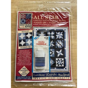 Op de afbeelding: Een in plastic verpakt pakket met een All Star quiltblok van de maand augustus 1997 genaamd Starry Sky, met blauwe en witte sterrenpatronen, en een apart klein pakketje met een witte en blauwe lederen vingerhoed.