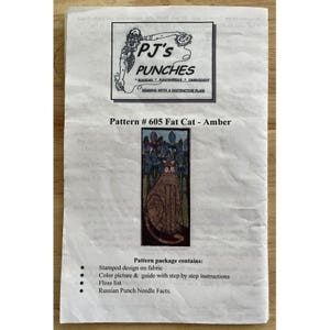 May include: A printed pattern for a fat cat design, labeled "Pattern # 605 Fat Cat - Amber." The pattern includes a stamped design on fabric, a color picture, instructions, a floss list, and Russian Punch Needle Facts. The PJ's Punches logo is at the top.