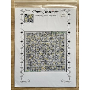 May include: A sealed plastic bag containing a cross-stitch kit. The kit features a detailed blackwork design with yellow and black floral and geometric patterns. The text "Tams Creations Blackwork: Round the Garden" is visible.