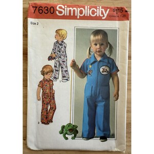 以下が含まれることがあります： 子供用ジャンプスーツのSimplicity縫製パターン7630。このパターンは、ジッパーとパッチが付いた青いジャンプスーツ、および他の2つのパターン化されたジャンプスーツを含む、3つの異なるジャンプスーツのデザインのイラストを特徴としています。サイズ2。