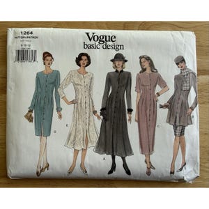 Peut inclure: Une pochette de patron de couture Vogue Basic Design 1264 présentant des illustrations de cinq styles de robes différents étiquetés de A à E. L'enveloppe en papier blanc affiche la marque, le numéro de patron 1264 et la taille 8-10-12 avec un code-barres.