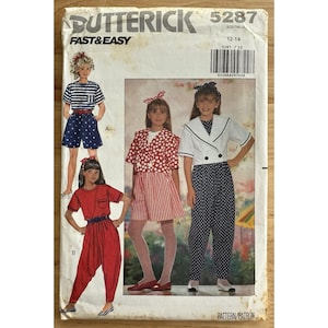 May include: Vintage Butterick sewing pattern 5287 for girls' clothing. The pattern features illustrations of various outfits, including shorts, a jumpsuit, and a sailor-style top and pants. The cover is off-white with the text "FAST & EASY" and "PATTERN/PATRON".