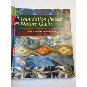 May include: A book titled "Foundation Pieced Nature Quilts" with a colorful quilt design on the cover. The cover features geometric patterns, nature scenes, and the names of the editors, Liz Schwartz and Stephen Seifert.
