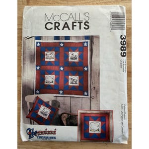 May include: A McCall's Crafts pattern envelope featuring a quilt and pillow design. The quilt has a red and blue star pattern with farm animal motifs. The envelope also shows a pillow with a similar design. The text "Homeland Treasures" is visible.