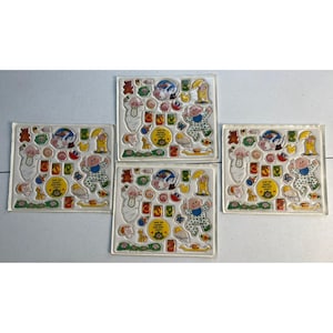 May include: Four sheets of vintage stickers featuring a baby theme. Each sheet has a variety of colorful stickers, including a baby in pajamas, a teddy bear, a globe, and other playful designs. The stickers are arranged on a clear, rectangular backing.
