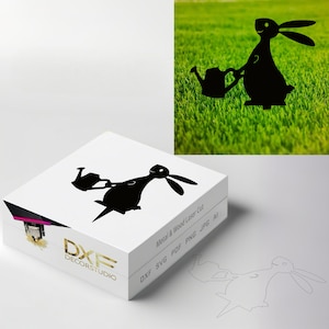 May include: Black silhouette of a rabbit holding a watering can. The image is on a white background with the text "DXF DECORSTUDIO" and "Metal & Wood Laser Cut" in black. The image is also on a green grass background.