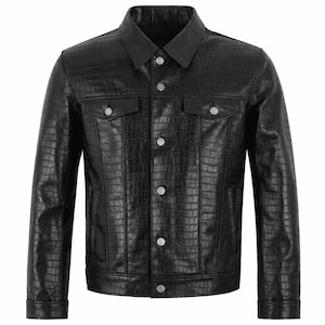 Könnte beinhalten: Schwarze Lederjacke mit Krokodilleder-Textur. Die Jacke hat einen klassischen Kragen, zwei Brusttaschen und silberfarbene Knöpfe. Das Design ist eine moderne Interpretation eines traditionellen Stils.