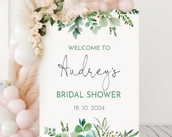 May include: White welcome sign with green watercolor floral border. The text reads "Welcome to Audrey's Bridal Shower 18. 10. 2024".