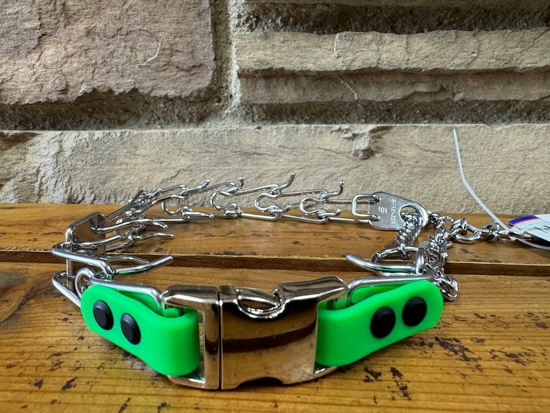 K&ouml;nnte beinhalten: Ein silbernes Stachelhalsband mit gr&uuml;ner Gummibeschichtung und einer silbernen Schnalle. Das Halsband hat ein Etikett mit der Aufschrift "Premier".