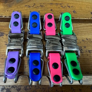 Op de afbeelding: Vier hondenriemen met zilveren gespen en drie zwarte stippen op elk. De riemen zijn paars, blauw, roze en groen.