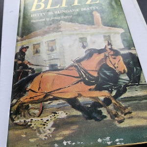 Puede incluir: Portada de libro vintage titulada "BLITZ" de Hetty Burlingame Beatty, ilustrada por Joshua Tolford. La portada muestra un carruaje tirado por caballos, un perro dálmata y una casa al fondo. El título está en letras doradas.