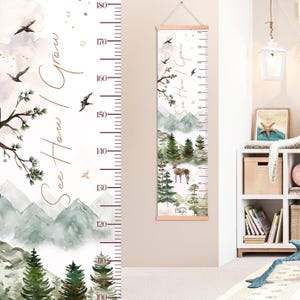 Puede incluir: Un medidor de altura de madera con una escena de bosque en acuarela, un ciervo y el texto "See How I Grow". El medidor mide hasta 180 cm, con un colgador de madera en la parte superior. El diseño incluye montañas, árboles y pájaros.
