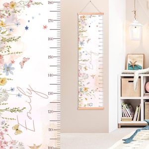 May include: A floral growth chart with wooden top and bottom, featuring a watercolor design of flowers, butterflies, and stars. The chart measures up to 180 cm and includes the name "Emily".