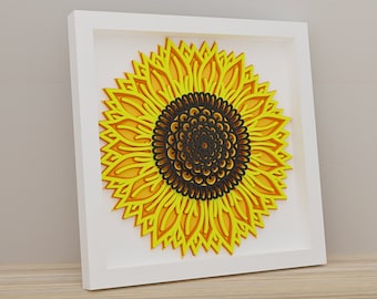 May include: A white framed wall art piece featuring a yellow and black paper cut-out sunflower.