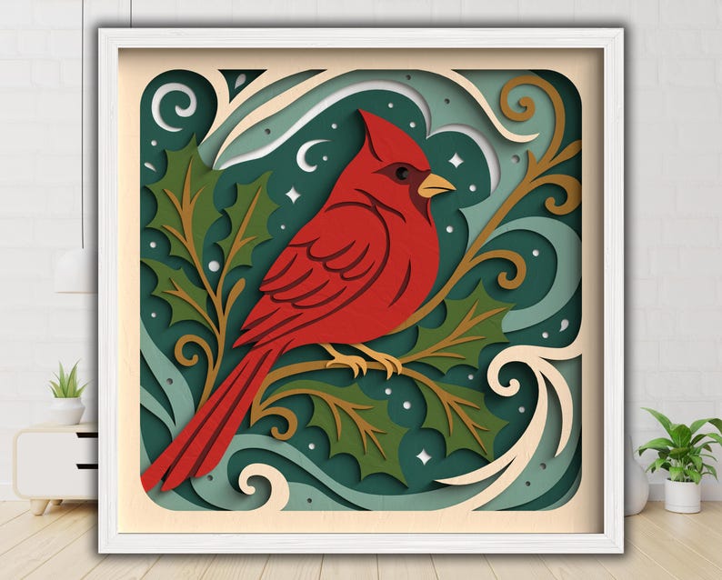 May include: A framed, layered paper art piece featuring a vibrant red cardinal perched on a branch with green holly leaves. The background has a teal and cream color scheme with decorative swirls and stars. The artwork is encased in a white frame.