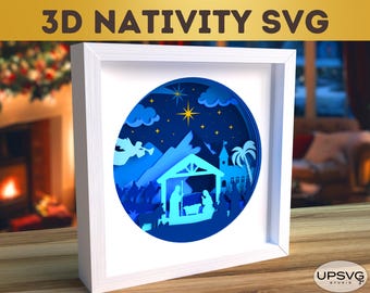 May include: A white frame with a blue and white 3D paper cut-out design of the nativity scene. The scene includes a star, a mountain, a palm tree, an angel, and a manger with Mary, Joseph, and baby Jesus.