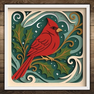 May include: A framed, layered paper art piece featuring a vibrant red cardinal perched on a branch with holly leaves. The background has shades of teal, cream, and gold, with a white frame. The artwork has a festive, nature-inspired theme.