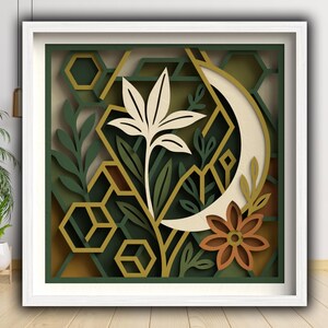 May include: A framed paper art piece with a layered botanical design. It features a cream-coloured flower, a crescent moon, and geometric shapes in green, gold, and brown. The artwork is presented within a white frame.