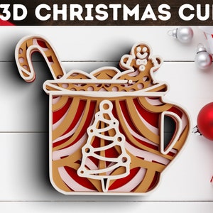 Könnte beinhalten: Ein 3D-Schnitzdesign aus Papier mit einem Weihnachtsbecher mit Zuckerstange, Lebkuchenmann und Weihnachtsbaum. Der Becher ist mit roten und weißen Streifen verziert.
