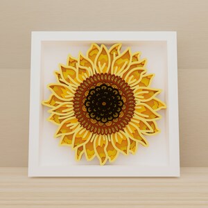 K&ouml;nnte beinhalten: Ein wei&szlig;er Rahmen mit einem gelben und braunen Papier-Ausschnitt-Sonnenblumen-Design. Die Sonnenblume hat eine detaillierte Mitte mit einem braunen und schwarzen Muster.