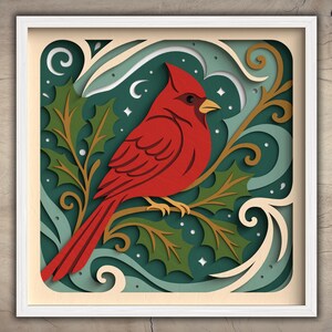 May include: A framed paper art piece featuring a vibrant red cardinal perched on a branch with green holly leaves. The artwork has a layered design with a teal background, white accents, and a white frame. The overall theme is nature and winter.