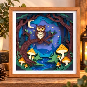May include: A square wooden frame containing a multi-layered paper art scene of a forest at night. A brown owl sits on a tree branch under a crescent moon and stars. Below, a blue stream flows through green grass with several yellow-spotted mushrooms.
