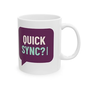 Könnte beinhalten: Ein weißer Keramikbecher mit einer dunkelvioletten Sprechblase auf der Vorderseite. In der Sprechblase steht der Text QUICK in Weiß und SYNC? in hellem Türkis, gefolgt von einem vertikalen Strich am Ende des Textes.