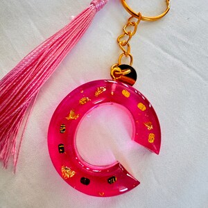 Portachiavi in resina, iniziale C, rosa brillante, pompon rosa e piccola medaglia dorata con punti dorati in carta ruvida