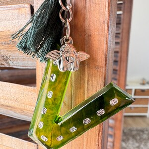 Portachiavi in resina con iniziale V, verde kaki e piccola medaglia d'oro con punti dorati in carta ruvida