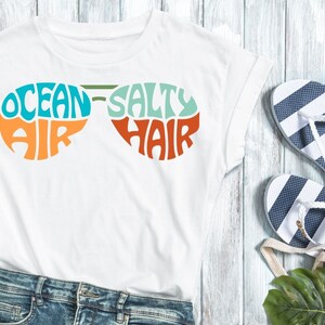 This design features the words Ocean Air Salty Hair, creatively made into the shape of sunglasses.