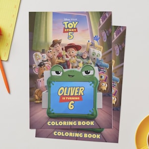 Pu&ograve; includere: Un libro da colorare a tema Toy Story 5 con una cornice per tablet a forma di rana verde sulla copertina. Lo schermo mostra il testo Oliver is turning 6. Lo sfondo mostra vari personaggi animati del film all'interno di una stanza.