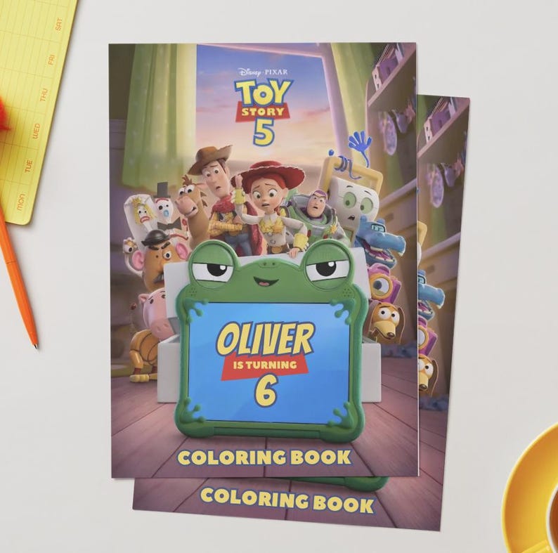 Pu&ograve; includere: Un libro da colorare a tema Toy Story 5 con una cornice per tablet a forma di rana verde sulla copertina. Lo schermo mostra il testo Oliver is turning 6. Lo sfondo mostra vari personaggi animati del film all'interno di una stanza.