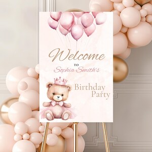 Op de afbeelding: Een roze en gouden welkomstbord met een teddybeer die een kroon en een tutu draagt. Het bord zegt "Welkom op Sophia Smith's verjaardagsfeestje".