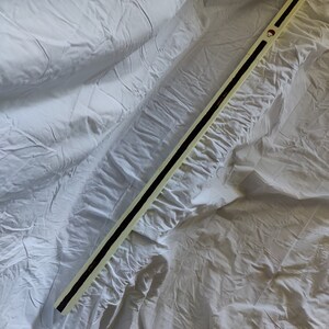 K&ouml;nnte beinhalten: Ein langer, wei&szlig;er Holzstab mit einem schwarzen Streifen, der in der Mitte verl&auml;uft. Der Stab hat einen roten Kreis oben.
